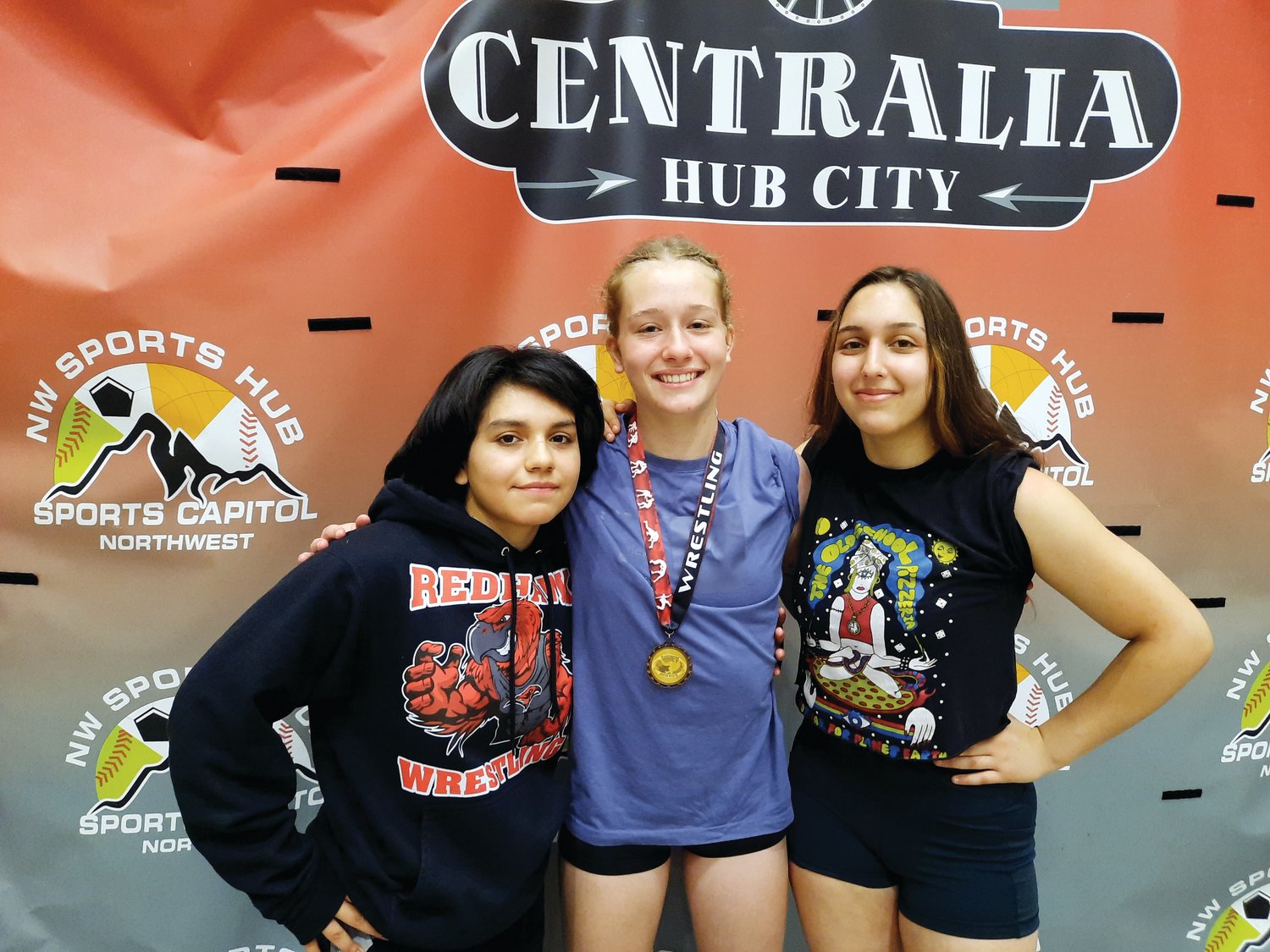 Lily Delgado, Savannah Hoffman, and Chloe Lampert gather for a photo at the Super State Wrestling championship in Centralia.